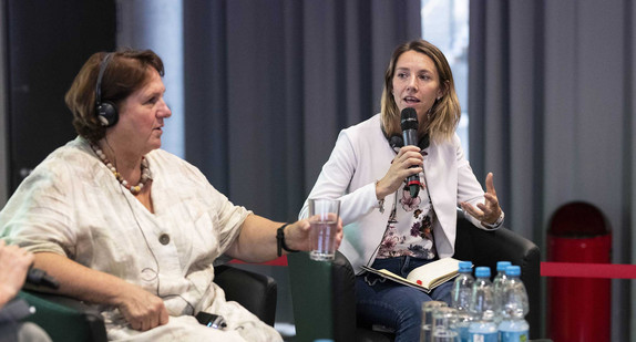 Kultusministerin Theresa Schopper und Marie-Amélie Le Fur sitzen auf Sesseln auf einer Bühne.